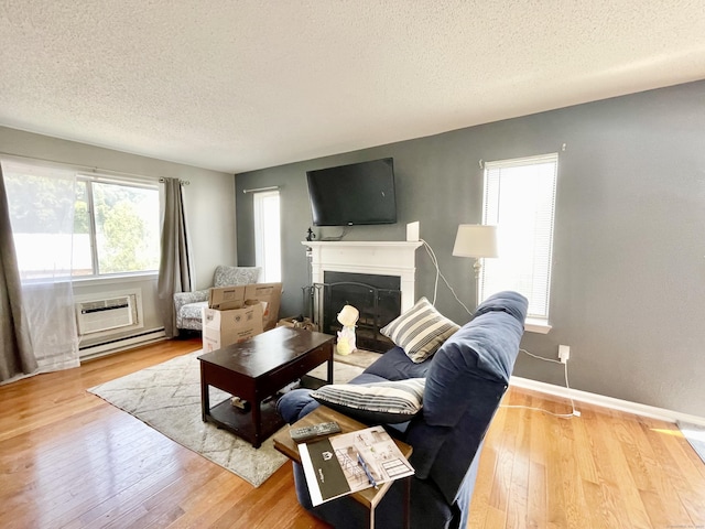 living room with hardwood / wood-style flooring, a wall unit AC, a textured ceiling, and baseboard heating