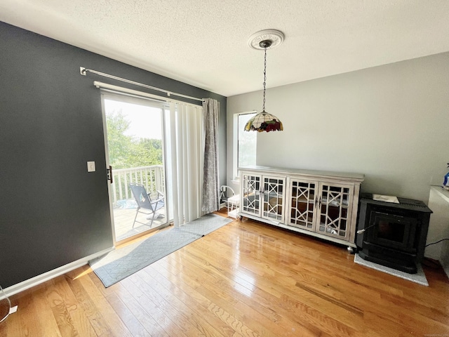 dining area featuring hardwood / wood-style floors, a textured ceiling, and a wood stove