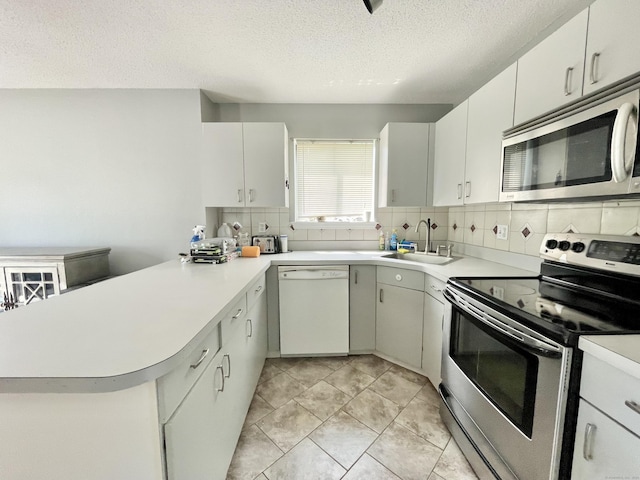 kitchen featuring appliances with stainless steel finishes, sink, white cabinets, and kitchen peninsula