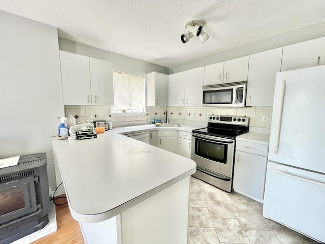 kitchen with stainless steel appliances, kitchen peninsula, and white cabinets