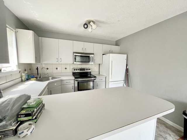 kitchen with sink, white cabinets, decorative backsplash, stainless steel appliances, and a textured ceiling