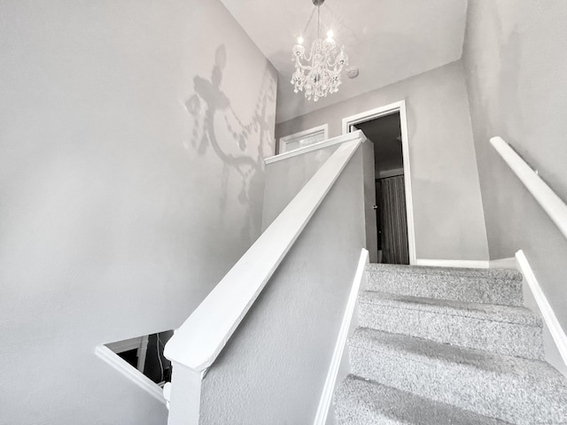 stairway with a chandelier and carpet