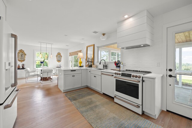 kitchen featuring a wealth of natural light, white appliances, and kitchen peninsula