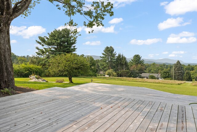 wooden deck featuring a mountain view and a yard