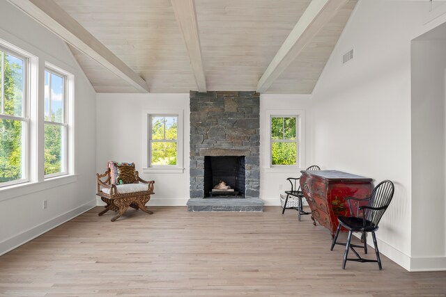 sitting room with vaulted ceiling with beams, a fireplace, light wood-type flooring, and a wealth of natural light