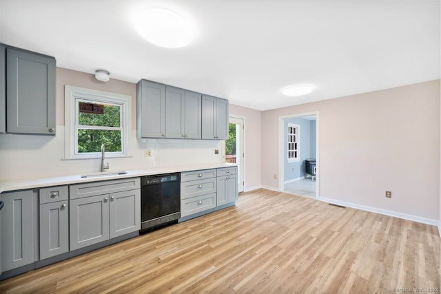 kitchen featuring light hardwood / wood-style floors, gray cabinets, dishwasher, and sink