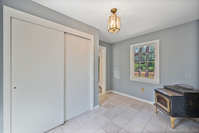 interior space featuring light tile patterned flooring, a closet, and a wood stove