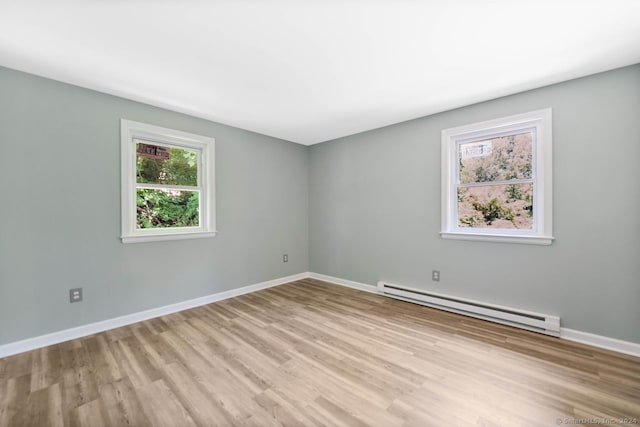 empty room with light hardwood / wood-style flooring and a baseboard heating unit