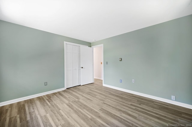 unfurnished bedroom with a closet and light wood-type flooring