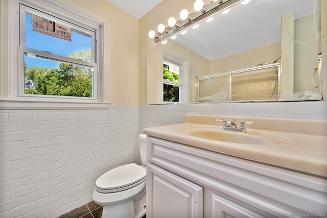 bathroom featuring tile walls, tile patterned flooring, vanity, walk in shower, and toilet