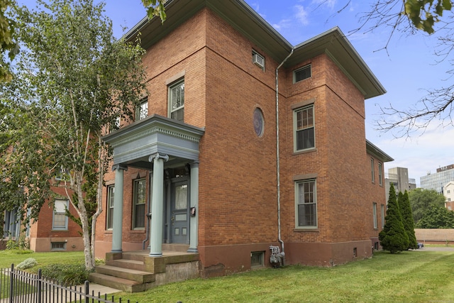 view of side of home with a yard, fence, and brick siding