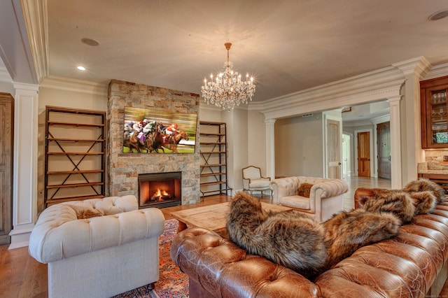 living room with a notable chandelier, wood-type flooring, ornamental molding, and a fireplace