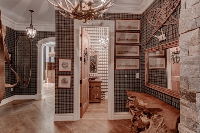 wine area with ornamental molding, light wood-type flooring, and decorative columns