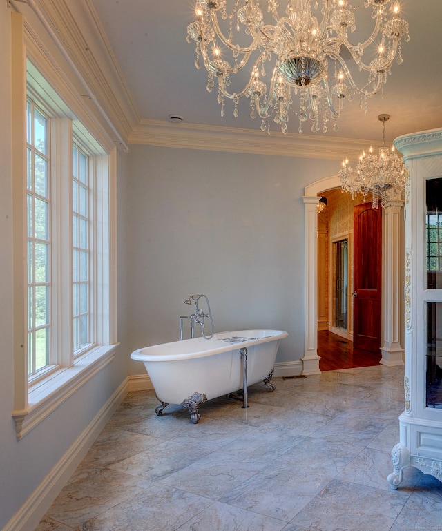 bathroom with ornamental molding, an inviting chandelier, a bathtub, and plenty of natural light