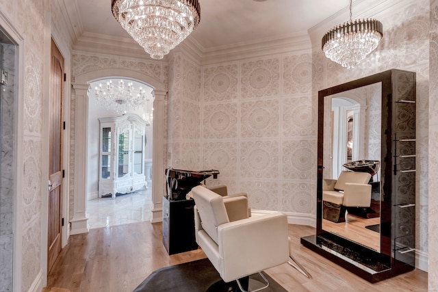 corridor with crown molding, hardwood / wood-style flooring, decorative columns, and a chandelier