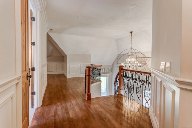 hallway with a notable chandelier, vaulted ceiling, and dark hardwood / wood-style flooring