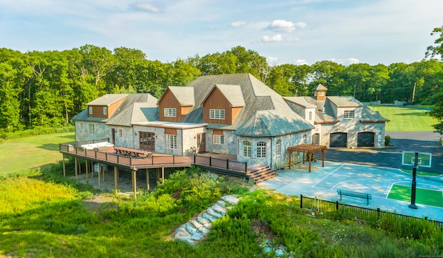 back of house with a yard, basketball court, and a garage