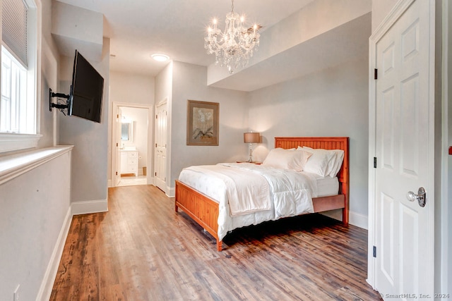 bedroom with hardwood / wood-style floors, ensuite bath, and a chandelier