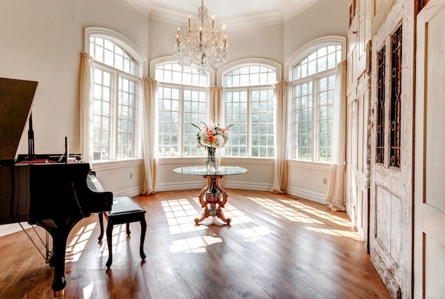 misc room with a notable chandelier, ornamental molding, light wood-type flooring, and a wealth of natural light