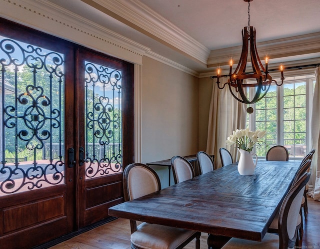 dining space with french doors, a notable chandelier, hardwood / wood-style flooring, and ornamental molding