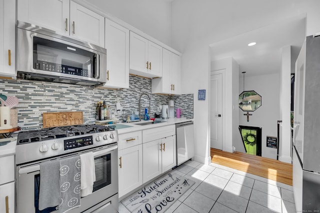 kitchen featuring white cabinets, sink, light tile patterned floors, and stainless steel appliances