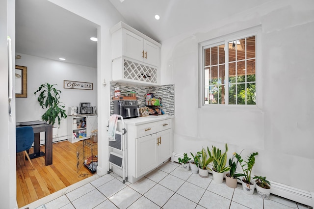 kitchen with white cabinets, decorative backsplash, light tile patterned floors, and baseboard heating