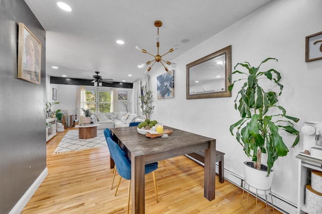 dining space featuring ceiling fan with notable chandelier, light wood-type flooring, and a baseboard radiator