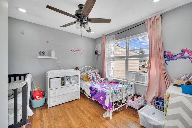 bedroom with ceiling fan, cooling unit, and wood-type flooring