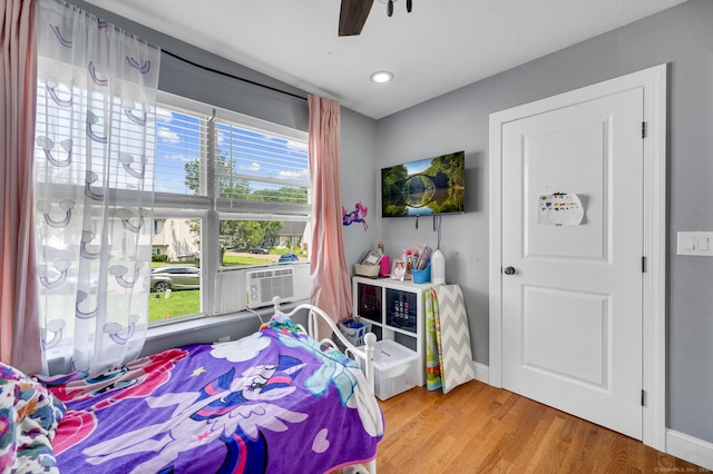 bedroom featuring ceiling fan, cooling unit, wood-type flooring, and multiple windows