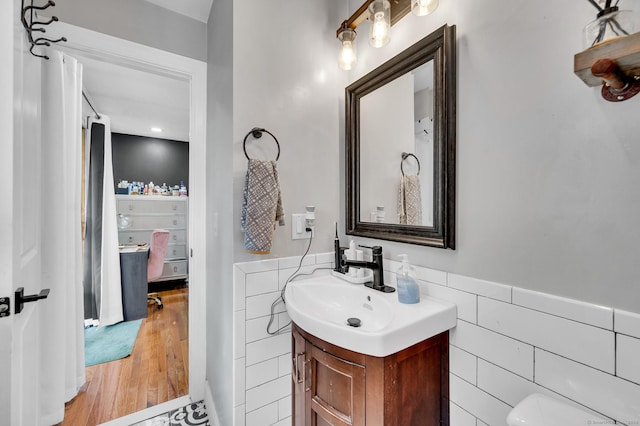 bathroom with wood-type flooring, vanity, and tile walls