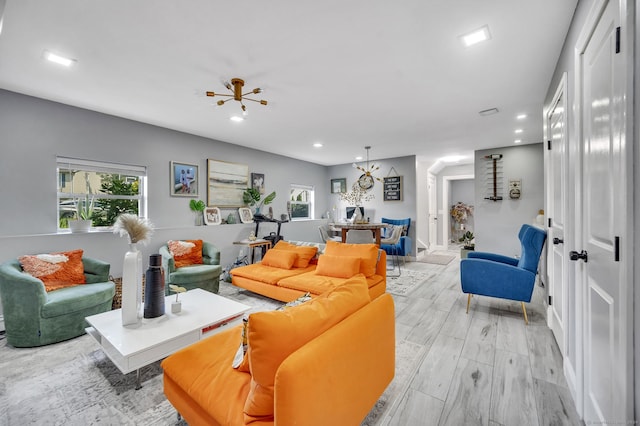 living room featuring a notable chandelier, light wood-type flooring, and a wealth of natural light