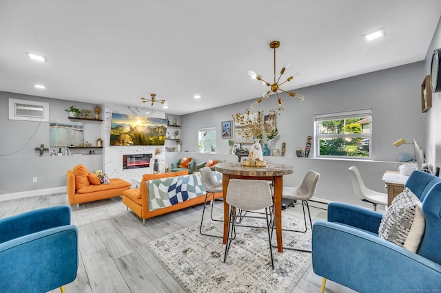 dining area featuring a notable chandelier, a fireplace, plenty of natural light, and light hardwood / wood-style flooring