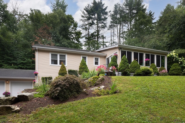 view of front of house with a garage, a sunroom, and a front yard