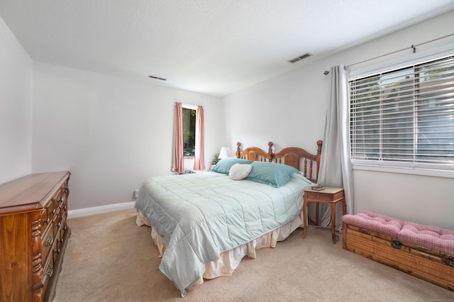 bedroom featuring multiple windows, light colored carpet, and a textured ceiling