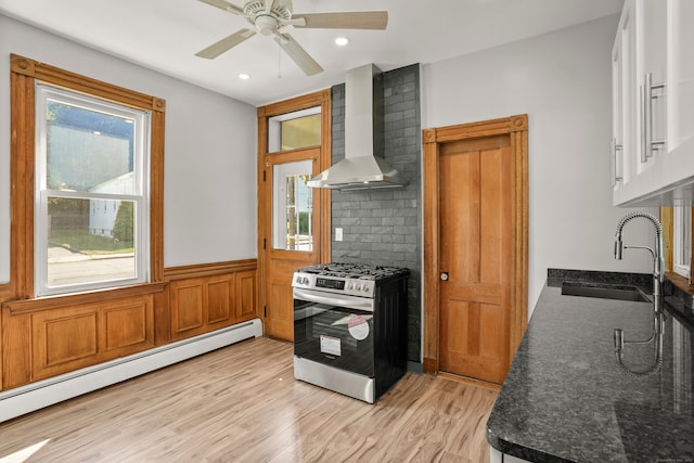 kitchen with gas range, wall chimney exhaust hood, baseboard heating, light hardwood / wood-style flooring, and sink