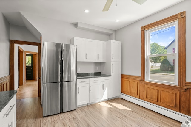 kitchen featuring light hardwood / wood-style floors, a healthy amount of sunlight, baseboard heating, and stainless steel fridge