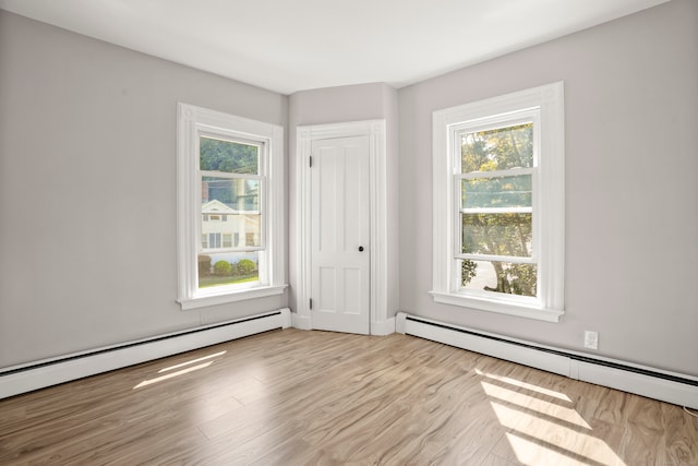 spare room with baseboard heating and light hardwood / wood-style flooring