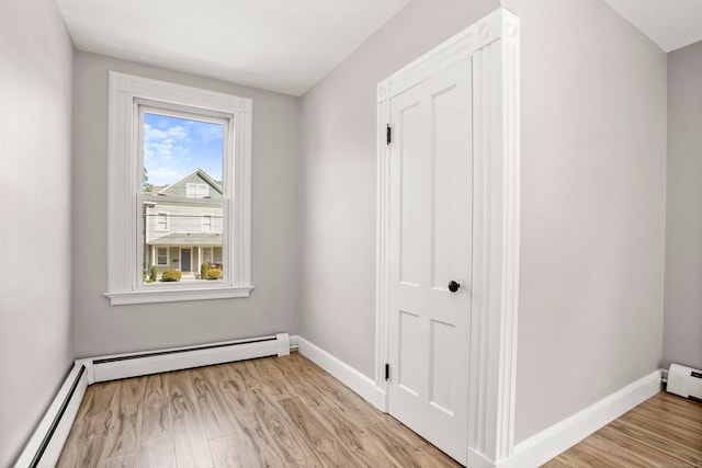 spare room featuring a baseboard heating unit and light hardwood / wood-style floors