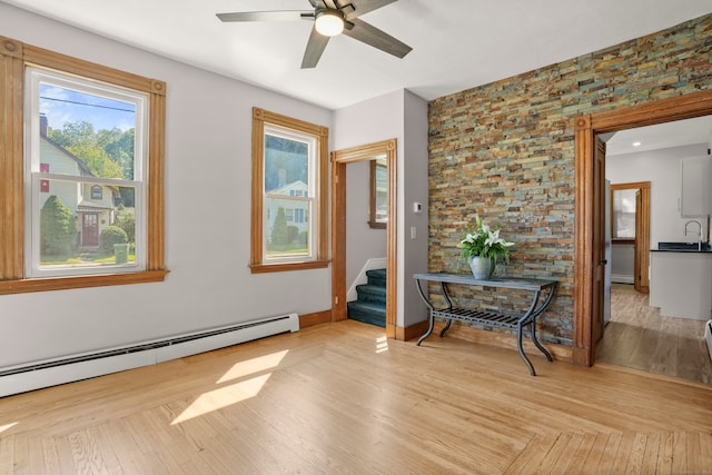 interior space with baseboard heating, sink, and light wood-type flooring