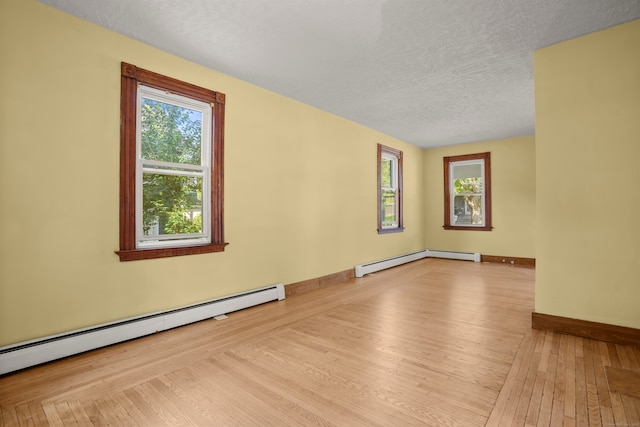 spare room with light hardwood / wood-style floors, a textured ceiling, and a baseboard radiator