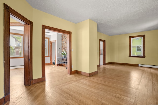 unfurnished room with a textured ceiling, a baseboard radiator, and light wood-type flooring