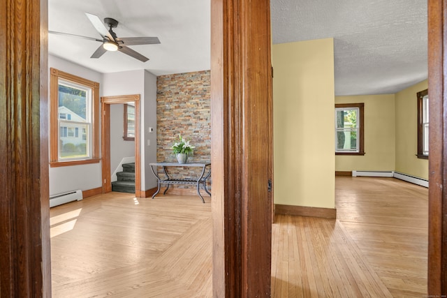 corridor with light hardwood / wood-style flooring, a textured ceiling, and a baseboard radiator