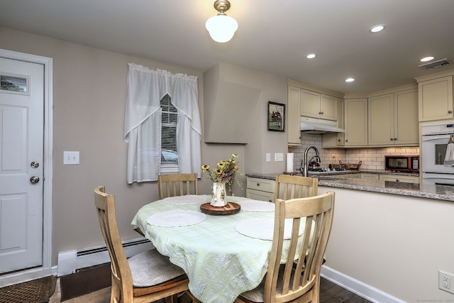 dining room featuring a baseboard heating unit and dark hardwood / wood-style floors