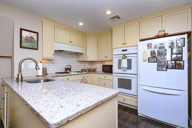 kitchen with white appliances, light stone counters, sink, dark hardwood / wood-style floors, and cream cabinetry