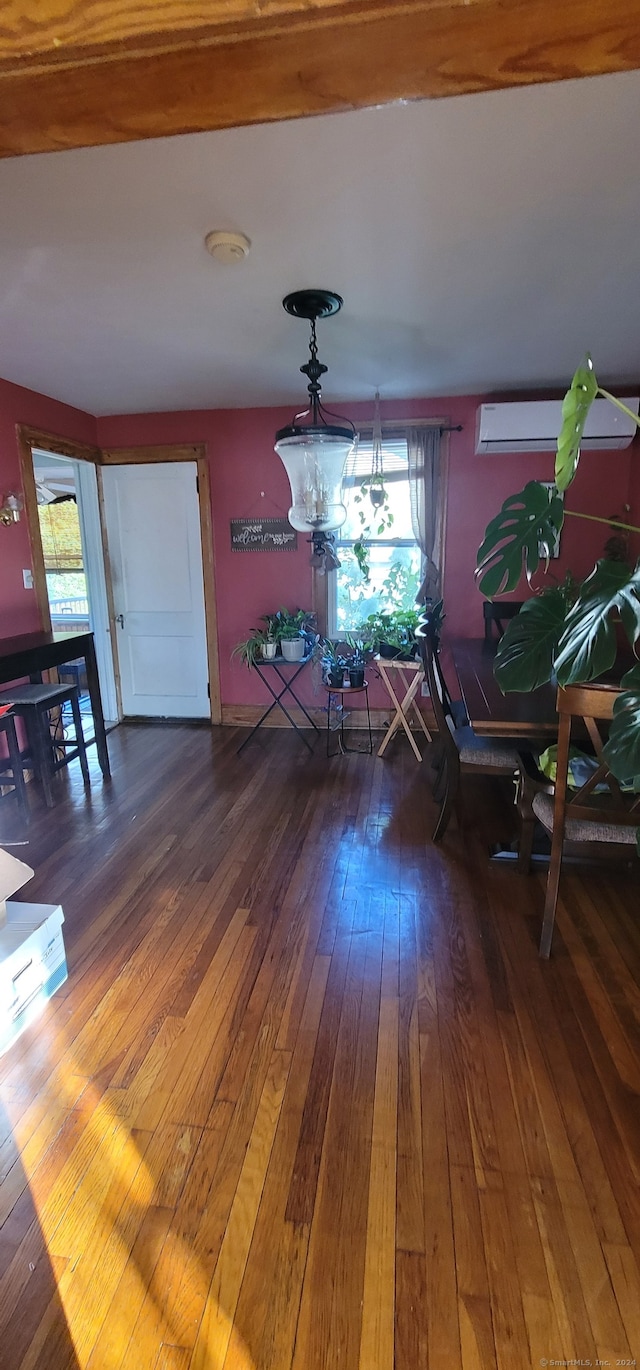 unfurnished dining area featuring wood-type flooring, a chandelier, and an AC wall unit