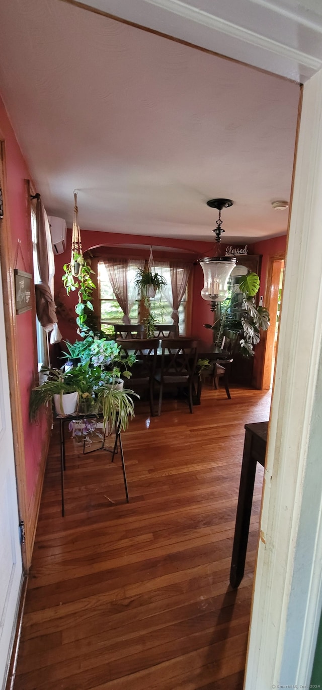 dining space with dark hardwood / wood-style flooring, an inviting chandelier, and an AC wall unit