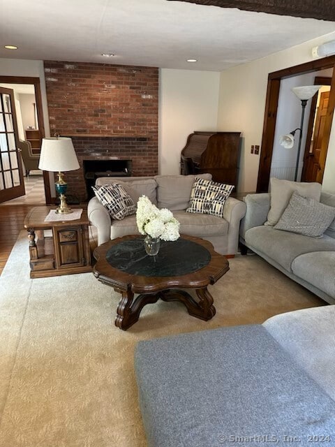 living room featuring brick wall, wood-type flooring, and a brick fireplace