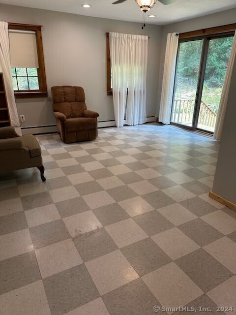 tiled living room with ceiling fan, a wealth of natural light, and a baseboard radiator