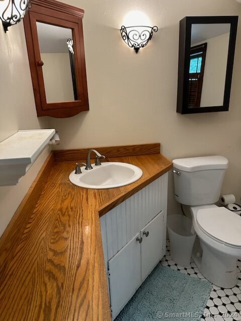 bathroom with toilet, vanity, and tile patterned floors