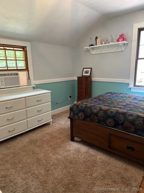 carpeted bedroom with vaulted ceiling, multiple windows, and cooling unit